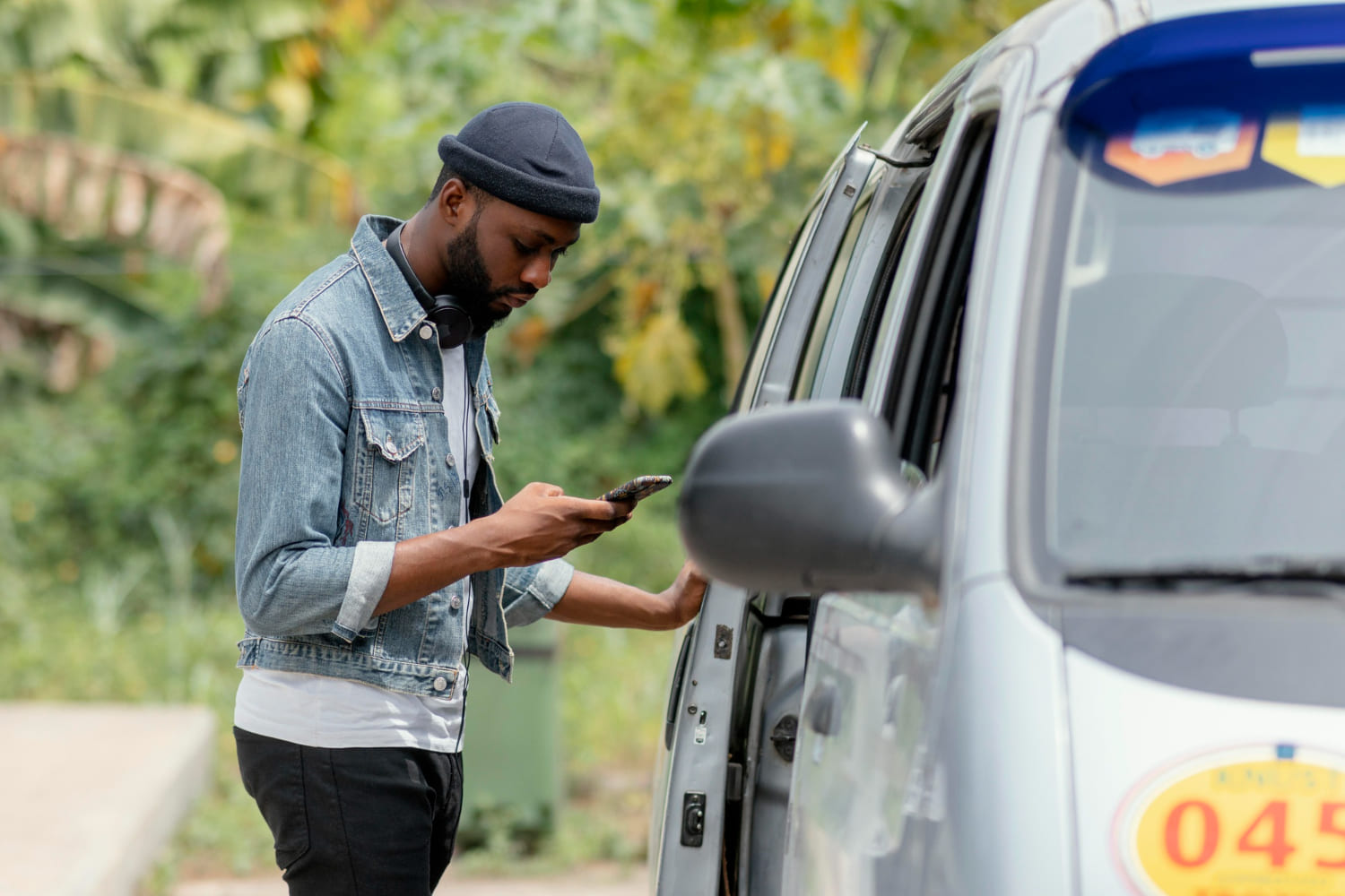Un usager règle son trajet via Mobila Ride depuis son téléphone, à côté de son taxi